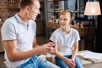 Happy father turning on music for his son in headphones