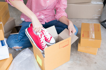 start up small business owner packing shoes in the box at workplace. freelance woman seller prepare product for packaging process at home.  Online selling, e-commerce concept
