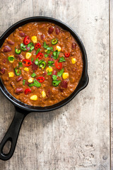 Traditional mexican tex mex chili con carne in a frying pan on wooden table.Top view
