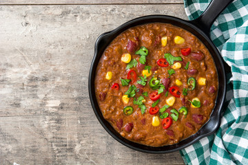 Traditional mexican tex mex chili con carne in a frying pan on wooden table.Top view
