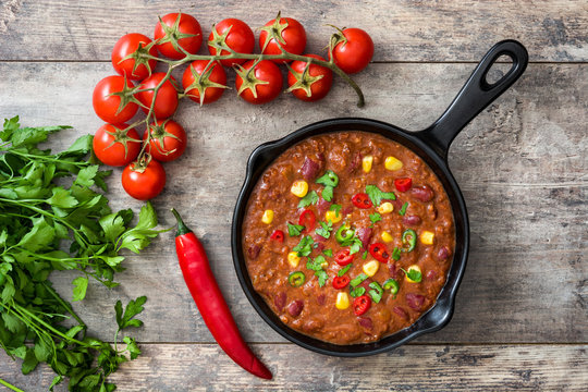 Traditional mexican tex mex chili con carne in a frying pan on wooden table.Top view
