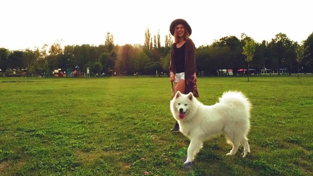 Girl playing with samoyed dog during walk at the park slow motion