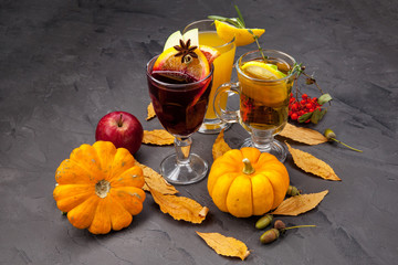 a still-life of alcoholic autumn warming drinks, cocktails, mulled wine with pumpkins, yellow leaves and rowan