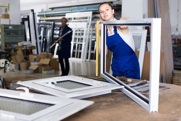 Fototapeta premium female worker measuring metal-plastic window frame in workshop