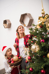 mother and daughter decorating christmas tree