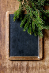 Vintage empty chalkboard with fir Christmas tree and small elk over wooden background. Top view with space for text