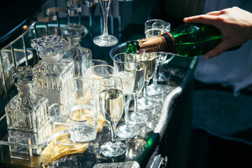 hand hold bottle of champagne and filling up glasses
