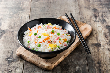 Chinese fried rice with vegetables and omelette on wooden table
