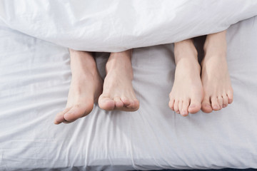 feet of couple stretching out of blanket