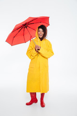 Full length image of pleased african woman in raincoat