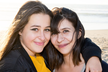 Mom with teen daughter receiving a hug on sand beach