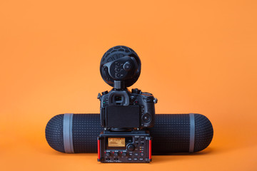 equipment for field video production, camera, boom mic and audio recorder on the orange background - 172110267