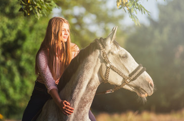 Woman riding a horse during sunset in countryside