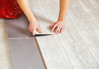Fototapeta na wymiar handyman's hands laying down laminate flooring boards