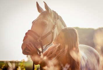 Woman hugging her horse at sunset, autumn scene