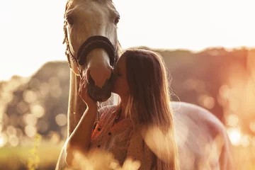 Zelfklevend Fotobehang Woman kissing her horse at sunset, outdoors scene © leszekglasner