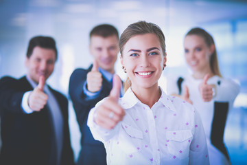 Happy business team showing thumbs up in office