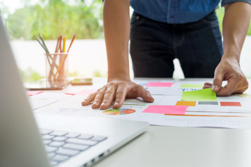 Office worker stands by the table analyzing the graphs.Hands placed on graph, other hand grab the flip chart.