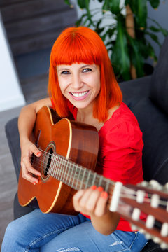 Relaxed redhaid woman playing guitar
