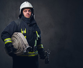 Naklejka premium Firefighter in uniform holds fire hose.