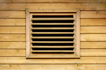 wooden ventilation grille on the facade of a wooden wall