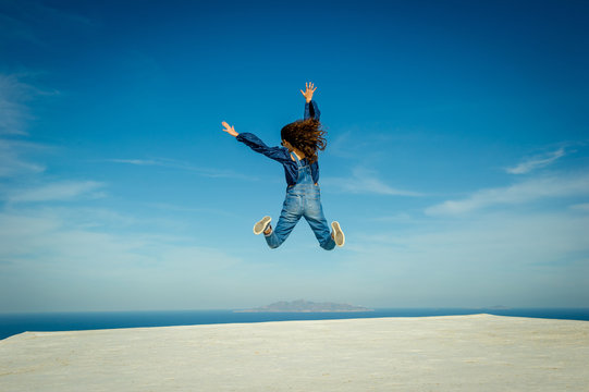 Girl in midair, sea and sky in background, Oa, Santorini, Kikladhes, Greece