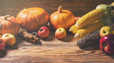 Autumn concept - pumpkins with colorful vegetables on wooden background