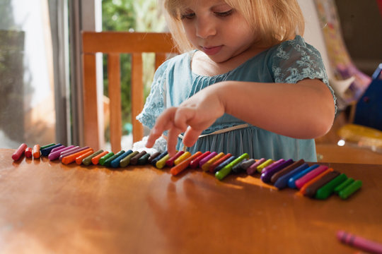 Girl lining up crayons in a row
