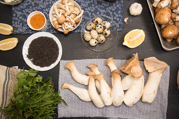 Group of raw ingredients for preparing vegetarian dinner.Oyster mushrooms, champignons, honey mushrooms, quail eggs, arugula, black sesame, lemon. Healthy food concept
