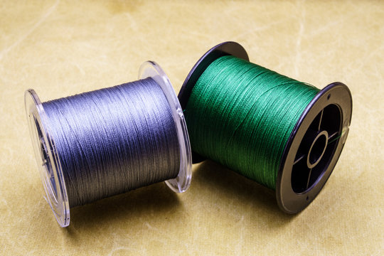 Spools of cords on the background of tarpaulin. Green and gray fishing line. Spools of braided fishing line