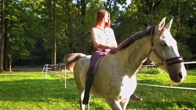 Young woman riding horse on green field