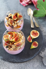 Fototapeta na wymiar Two glasses of fruit yogurt with granola, figs and honey for light breakfast