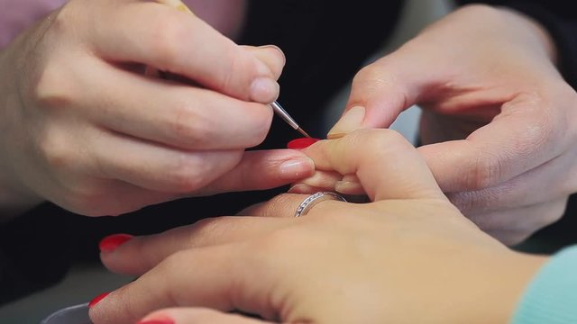 manicure making female hands, covering of transparent enamel and red nail varnish, nail polish.Woman hands in a nail salon receiving a manicure by a beautician. Woman getting nail manicure.