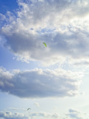Two paragliders fly against the background of the evening sky. Vertical image