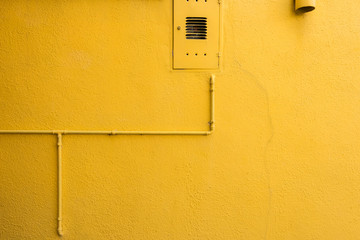 Beautiful colorful house facade on Burano island, north Italy. Vivid yellow wall with cracks and pipes