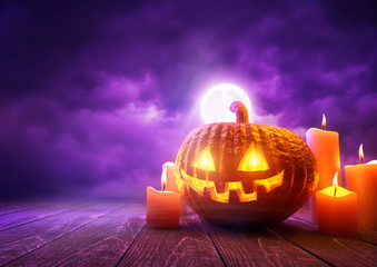 A glowing Pumpkin Jack-O-Lantern against purple sky background on Halloween, mixed media illustration. © James Thew