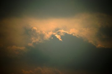 Fototapeta na wymiar cloudy day sun hiding going behind dim light slight yellow orange blue dusk
