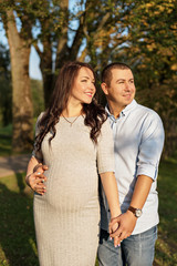 Fototapeta premium couple family in the expectation of a baby hugging in the city in sun rays