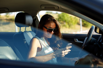 Attractive woman texting in a car on the road