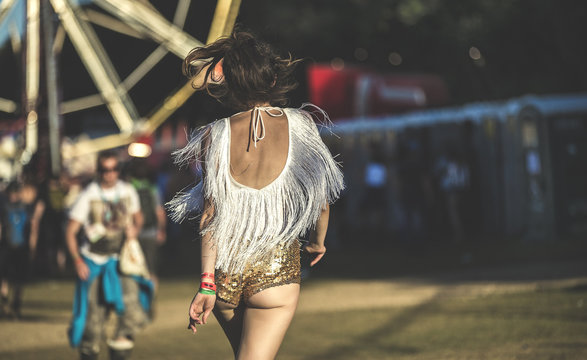 Rear view of young woman at a summer music festival wearing golden sequinned hot pants.