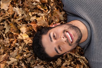 Overhead of man lying on autumn leaves