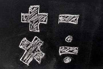 White chalk drawing in basic mathematics symbol (plus minus multiply divide) on black board...
