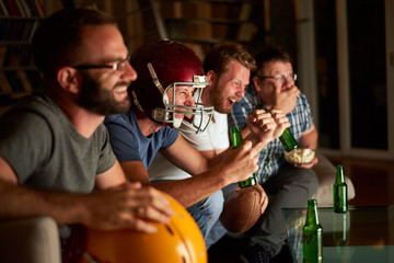 Four friends watching american football game on television