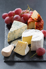 molded cheeses and grapes on a blackboard, close-up