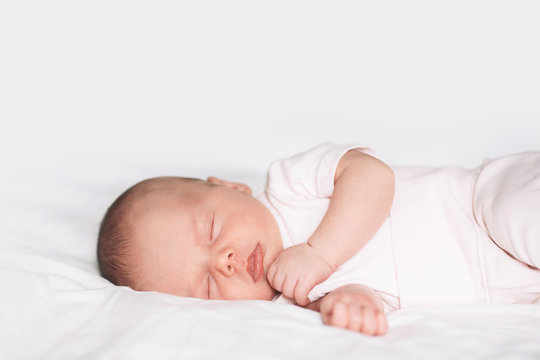 Sleeping newborn baby on white blanket.