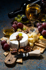 snacks, wine and Camembert cheese on a dark background, vertical