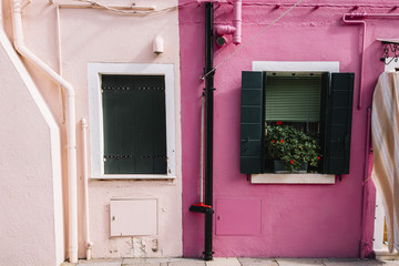Beautiful colorful house facade on Burano island, north Italy. Half pastel tender pink half magenta house wall with pipes and windows