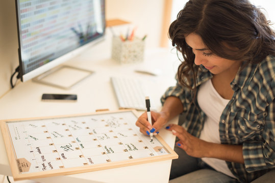 Woman On Computer Desk Writing On A Calendar