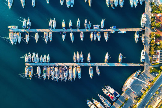 Fototapeta Aerial view of amazing boats at sunset in Marmaris, Turkey. Minimalistic landscape with boats and sea in marina bay. Top view from drone of harbor with yacht, motorboat and sailboat. Beautiful port