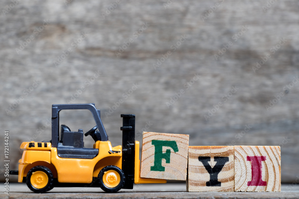 Poster Yellow plastic forklift hold letter F to complete word FYI (Abbreviation of For your information) on wood background